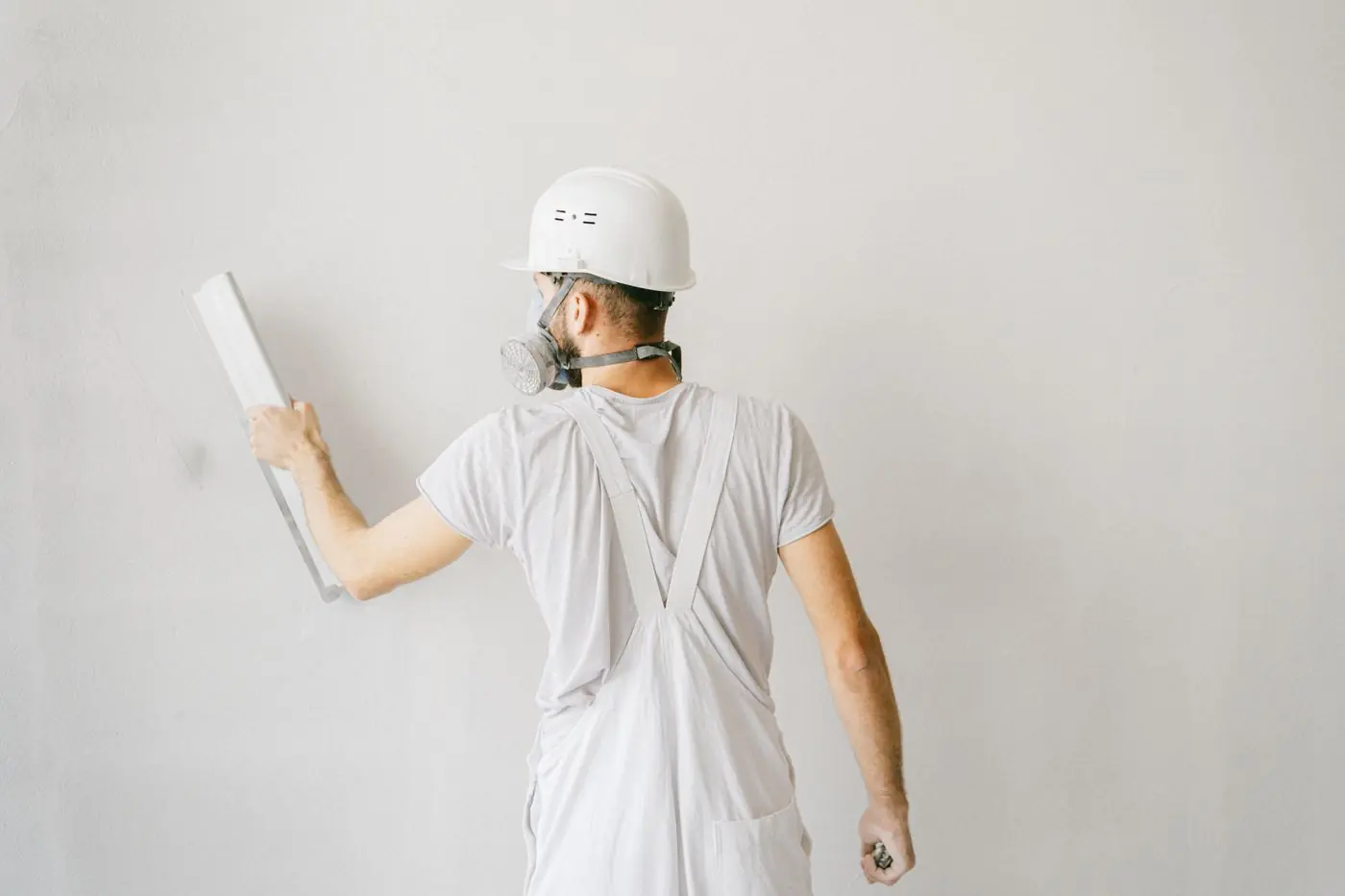 Stukadoor werkt een witte wand af met een pleisterspaan
